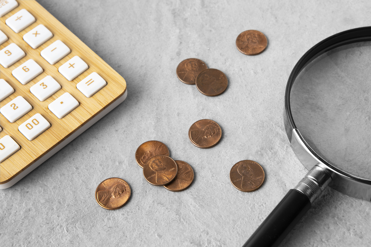 Coins, a calculator, and a magnifying glass on the table.