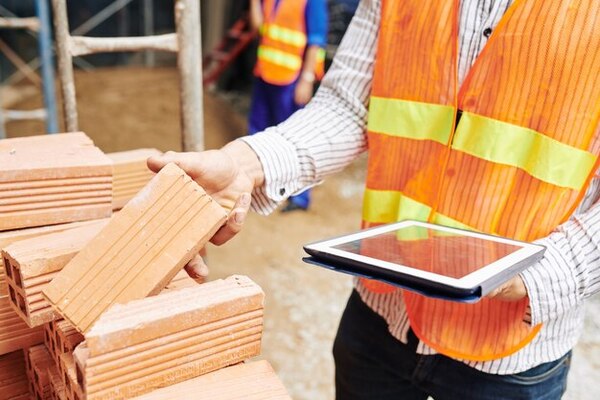 A construction worker considering bricks as materials for the construction project