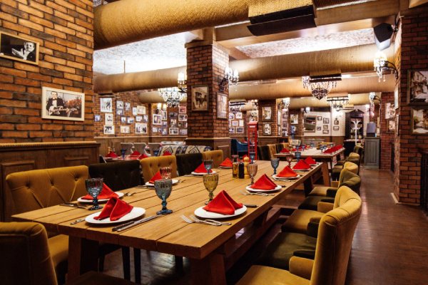 a newly remodel restaurant hall with red brick walls, tables, and pipes