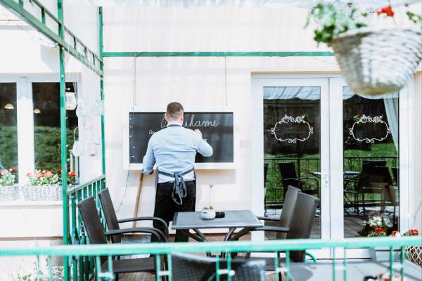 backview of a barman writing on chalkboard in a restaurant