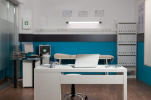 Modern medical exam room with desk and equipment setup.