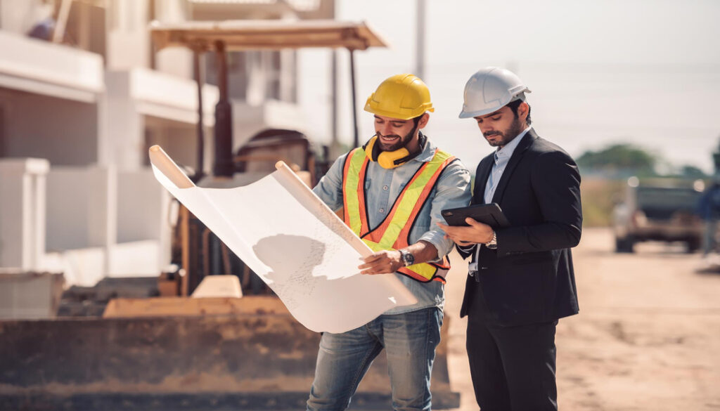• Workers at a construction site, wearing hard hats and reviewing detailed plans, highlight the importance of quality checks in building a restaurant.