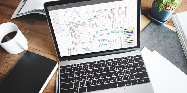 Laptop screen shows retail space build-out design next to coffee and notepad.