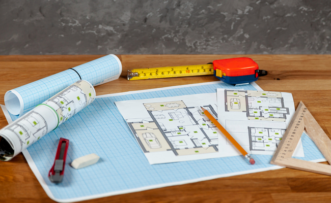 Retail space build-out plans with tools, blueprints, and layout drawings on a desk.